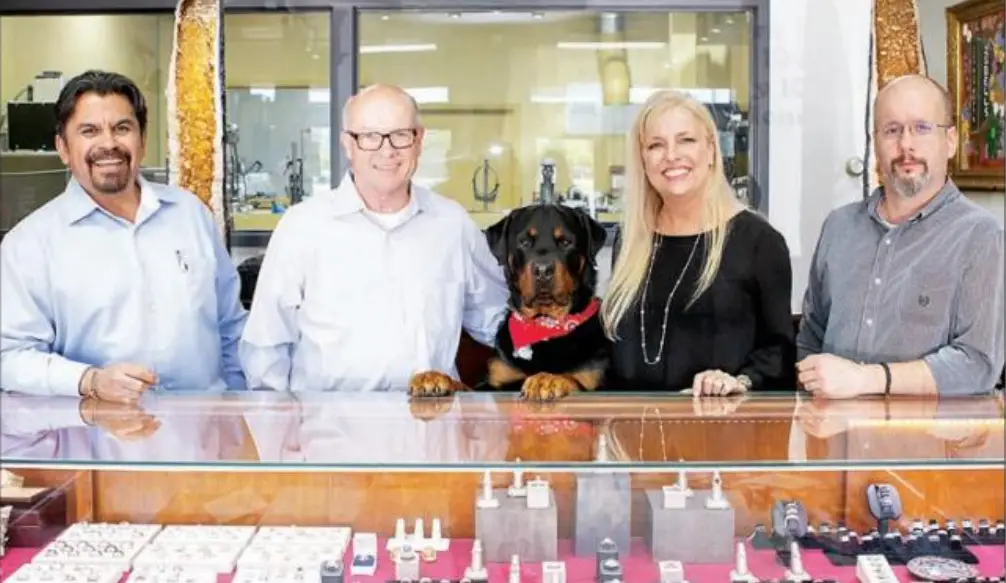 the owners and staff of Isbell Jewelers standing behind a jewelry counter filled with custom jewelry