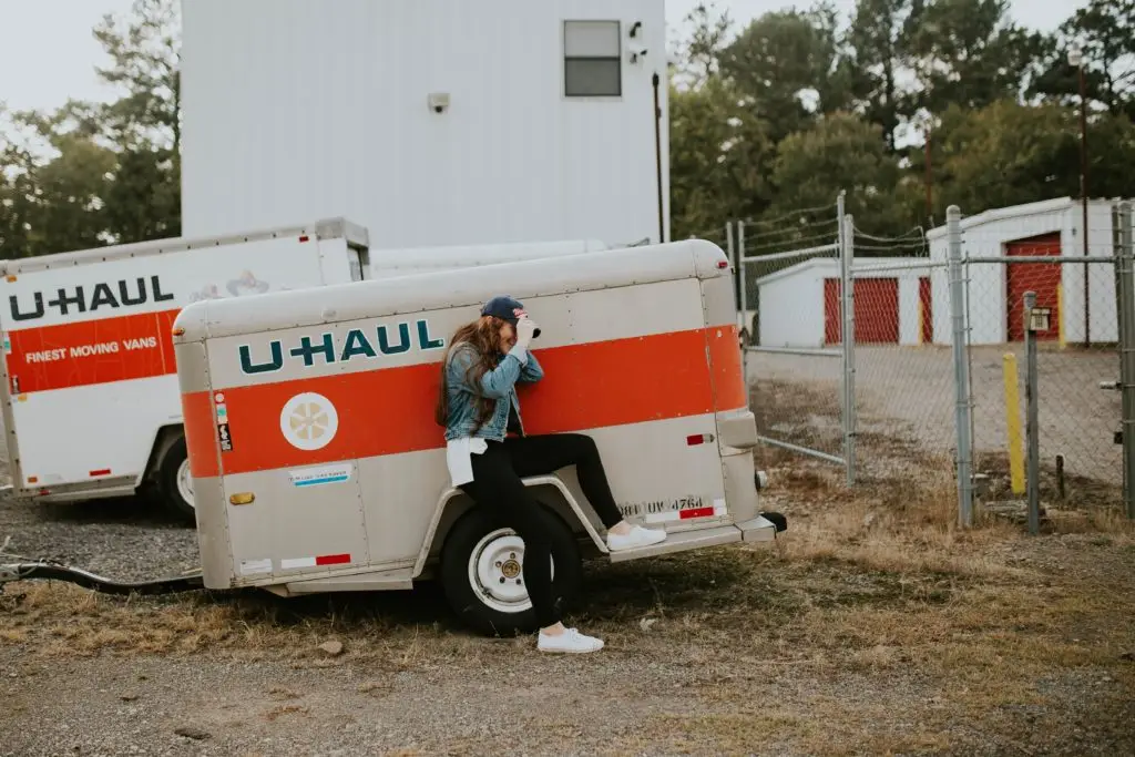 woman sitting next to a uhaul trailer in a parking lot