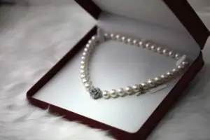 pearl necklace with a diamond pendant in a red jewelry box with white lining