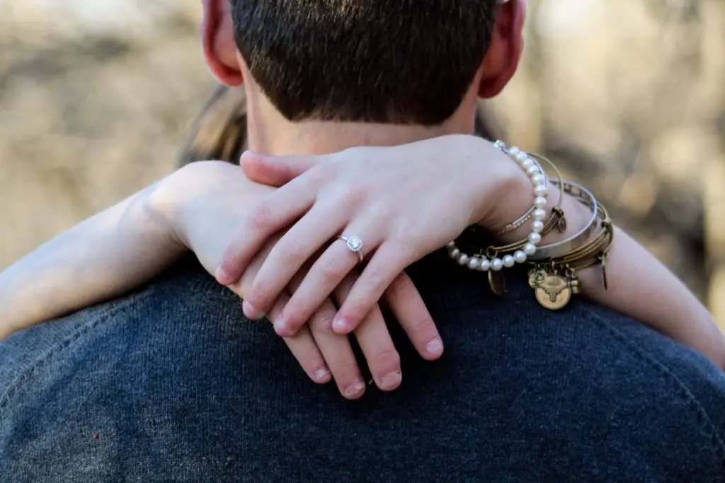 girl hugging a man and showing off her engagement ring