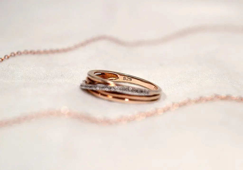 stack of rose gold ring bands surrounded by a rose gold chain on a light background