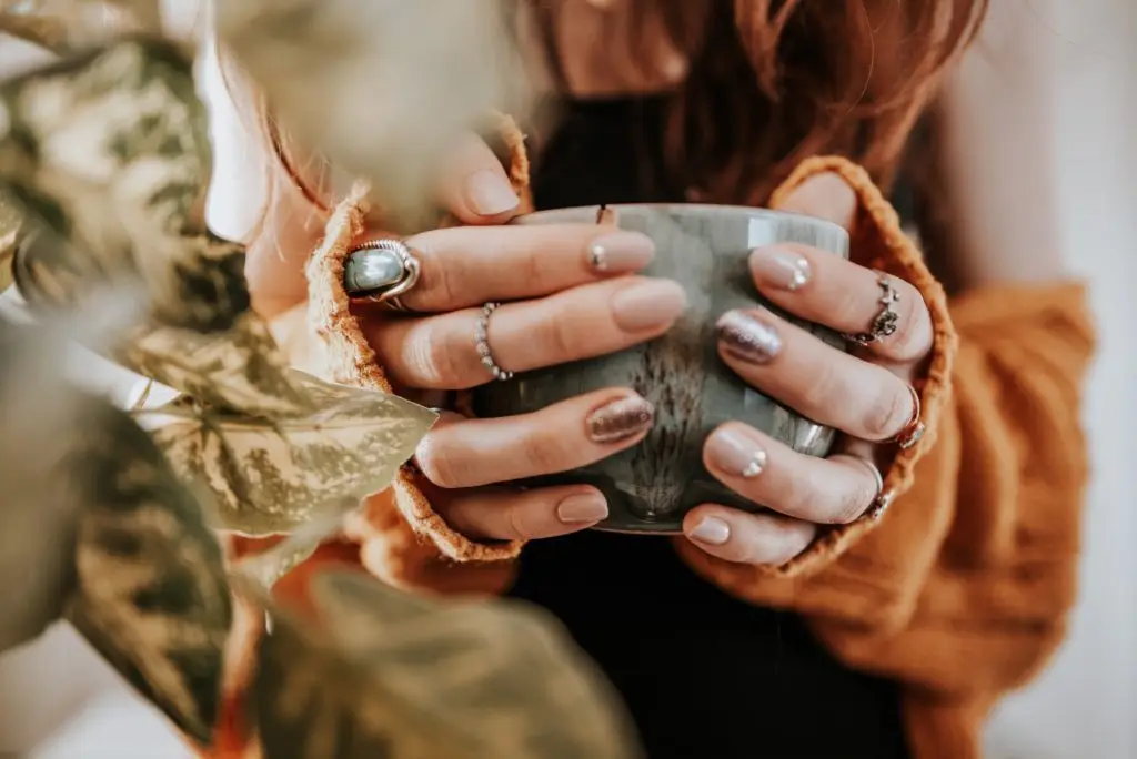 closeup of woman holding a mug while wearing different rings