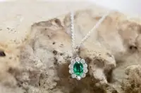 emerald oval pendant surrounded by diamonds on a silver chain