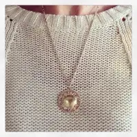 woman wearing a white sweater and a gold medallion locket