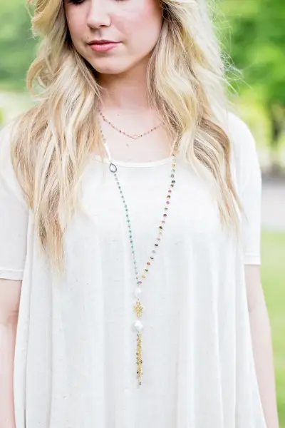 blonde woman wearing long multi-color necklace with tassel