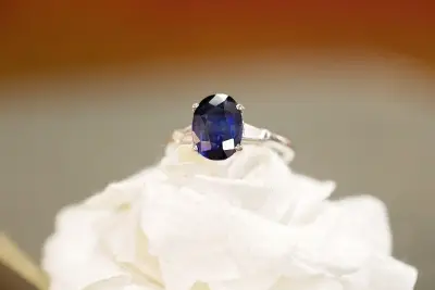 oval sapphire ring placed on a white flower