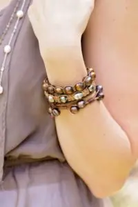 closeup of single row leather & pearl bracelets on a woman's wrist