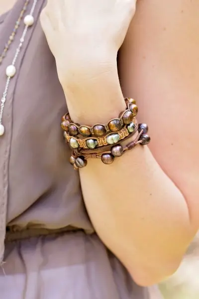 closeup of single row leather & pearl bracelets on a woman's wrist