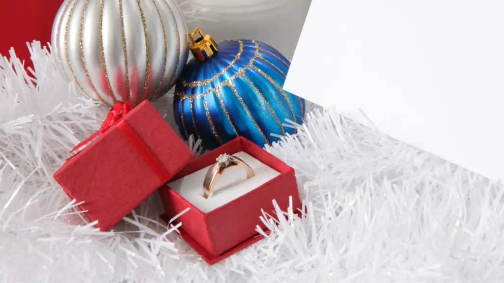 gold diamond ring in a red jewelry box in a christmas tree as a holiday gift