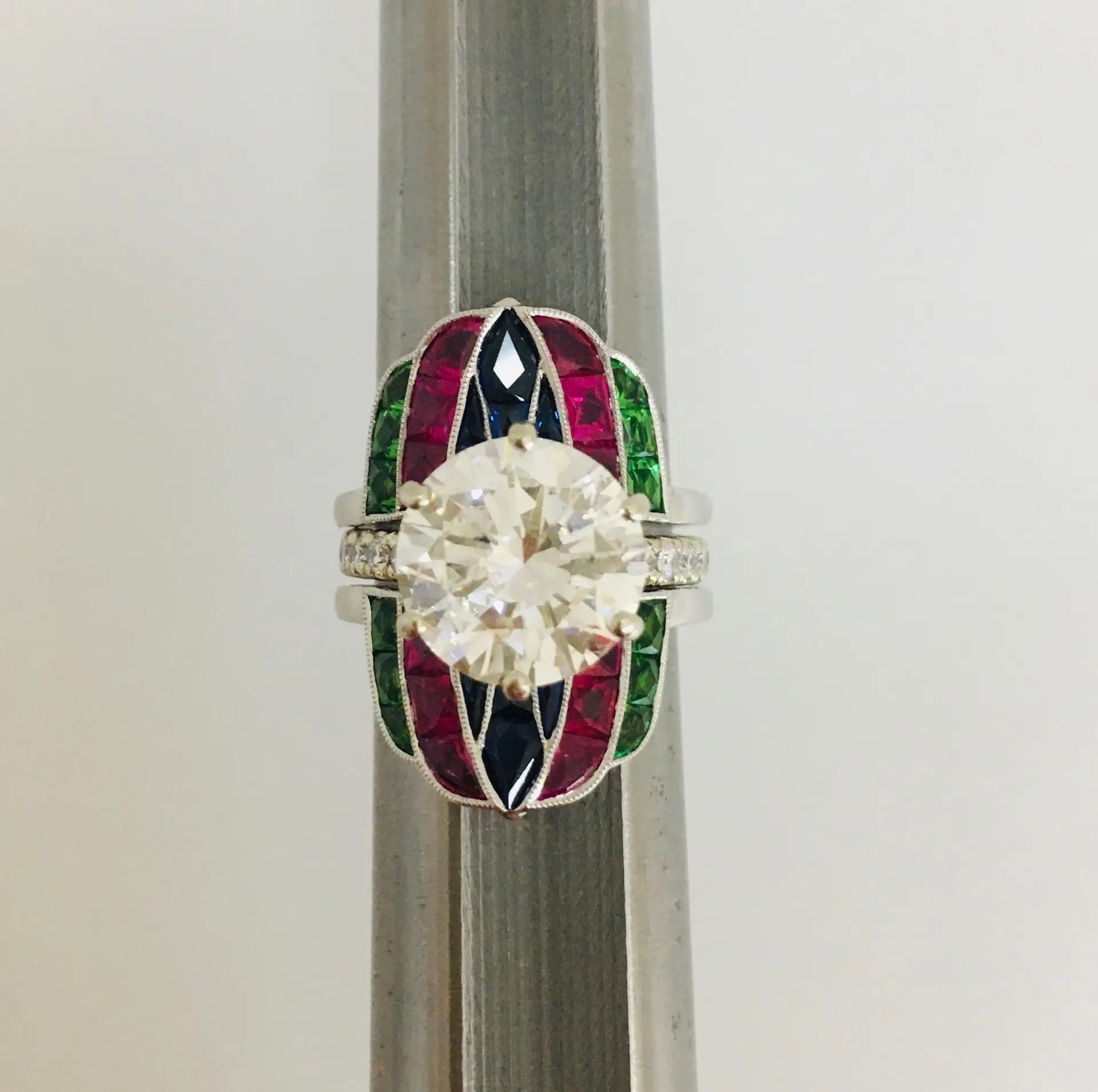 a ring wrap with a diamond in the middle and green, pink, and dark blue accents surrounding the diamond