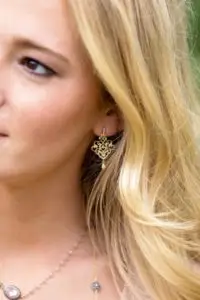 gold scroll drop earrings worn by a woman.