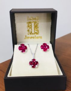 ruby gemstone and diamond earring and necklace set placed in a black isbell jewelers box 