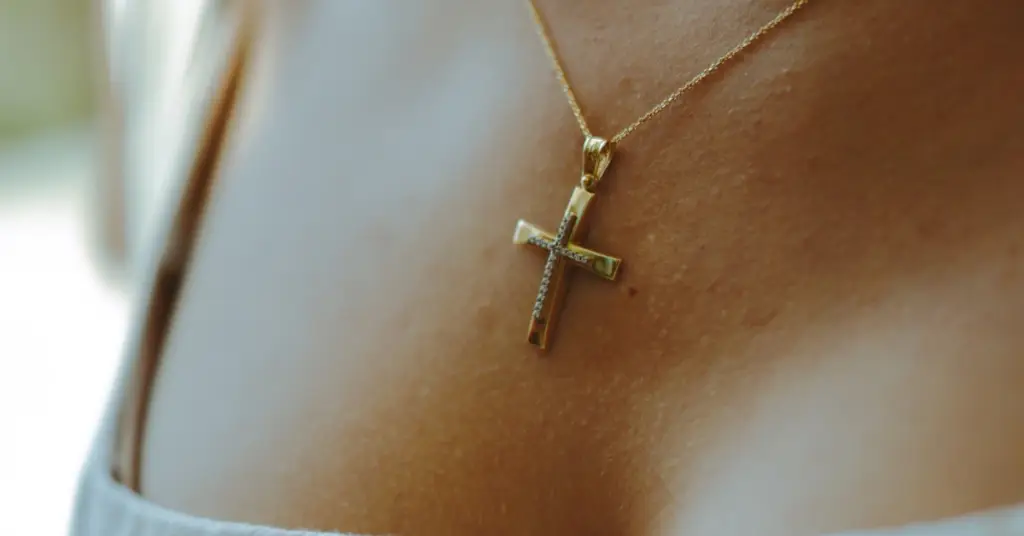 a gold cross necklace draped around a woman's neck