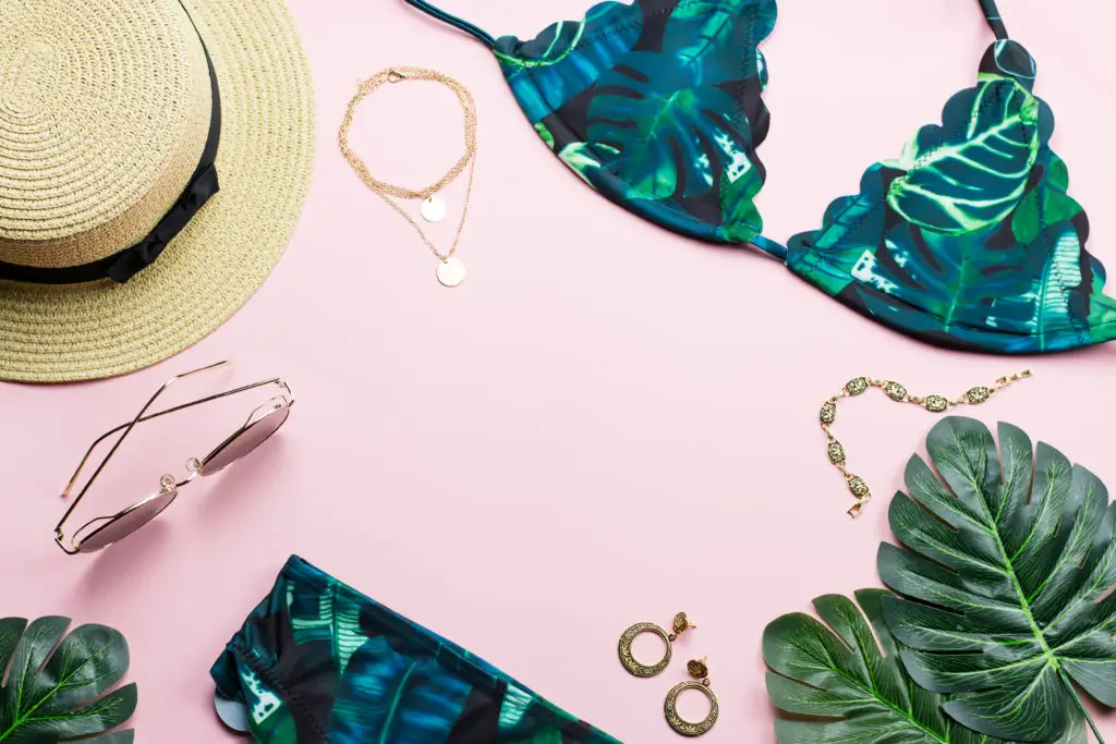 jewelry for the beach laid alongside a bikini, hat, and sunglasses