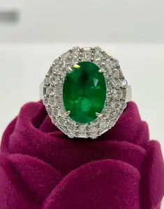 an emerald ring with white diamond surrounding it in white gold