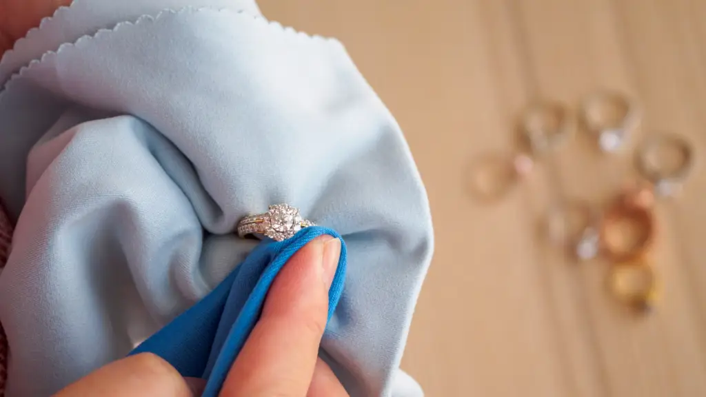 a woman's hand holding a diamond ring while cleaning it the jewelry with several rings blurred in the background