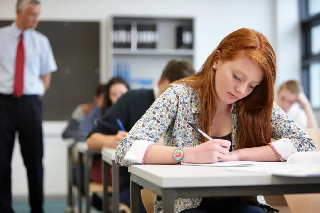 female student in a classroom wearing the latest back-to-school jewelry trends while taking notes