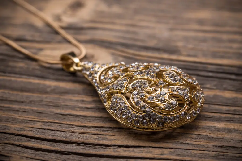 an antique necklace in gold sits on a wooden table