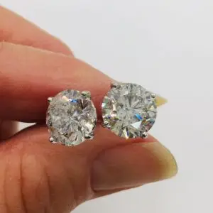 close up of diamond stud earrings in a woman's hand