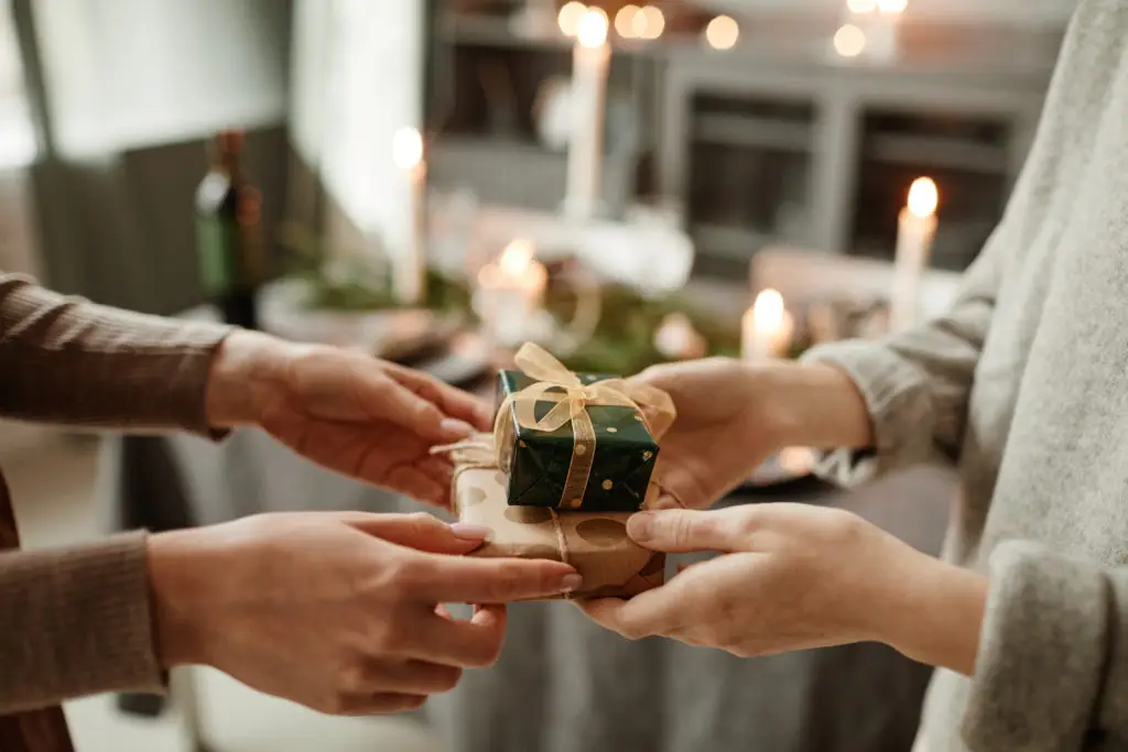 hands exchanging jewelry gifts with a christmas themed table in the background