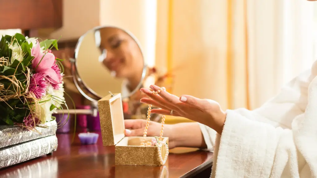 woman mixing and matching jewelry from her jewelry box on her dresser