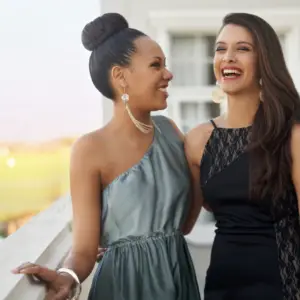 2 young girls smile and laugh in their prom dresses wearing statement earrings