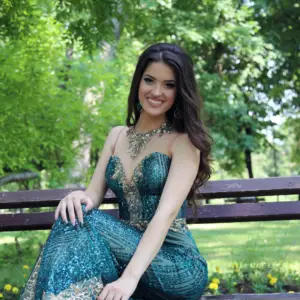 girl in emerald green prom dress seated with an emerald statement necklace and long emerald earrings