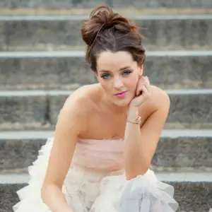 Young girl in her prom dress with hand under her chin showing off her prom bracelets