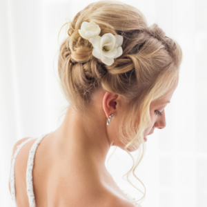 A back view of a modern bridal jewelry style with an embellished strap dress and small diamond earrings with flowers in her hair