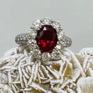 A red ruby gemstone ring surrounded by white diamonds