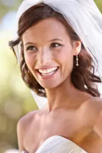 a headshot of a traditional bridal jewelry style with a veil and small diamond pendant earrings