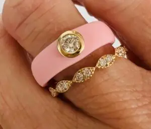 A pink silicone wedding band with a diamond in the middle paired with a diamond band