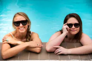 Two ladies in a swimming pool wearing their diamond silicone wedding bands and smiling 