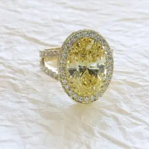 A large oval shaped canary yellow diamond ring surrounded by white diamonds