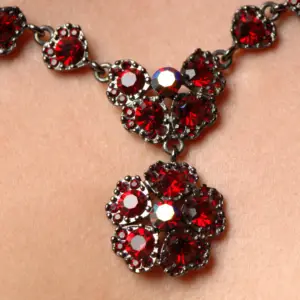 A close up view of an ornate ruby necklace in a flower design