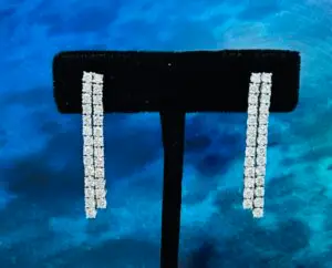 Diamond double bar earrings on black stand with blue background