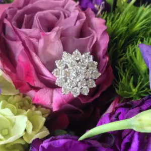 A diamond ring in the shape of a snowflake set among flowers 