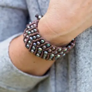 Gray pearls in a leather cuff bracelet on a woman's wrist