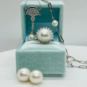 A pearl set of jewelry in a teal box with pearl studs, a pearl ring, and a pearl necklace for Valentine's Day