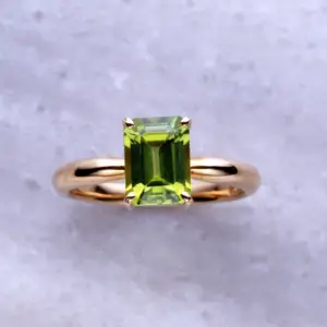 A peridot gemstone ring in an emerald cut set in yellow gold