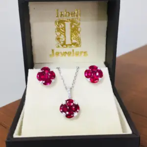 Ruby gemstones earrings and a ruby pendant in an open jewelry box from Isbell Jewelers