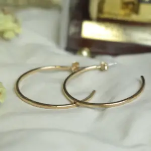 Large gold hoop earrings laying on a white cloth