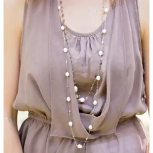 A long strand of a pearl necklace around a woman's neck 