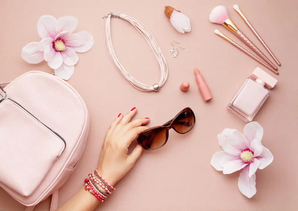 pink background with women's accessories, jewelry, sunglasses and flowers showing 2024 spring jewelry trends