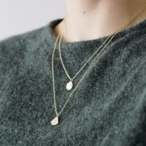 Two gold necklaces layered over a sweater