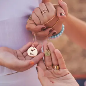 mother and daughter hold hands while holding lockets with their names engraved on them