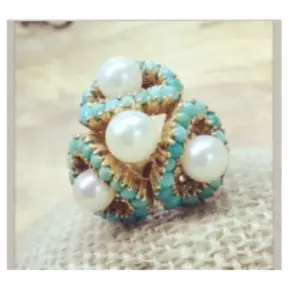 a vintage ring featuring 4 pearls each surrounded by turquoise gemstones