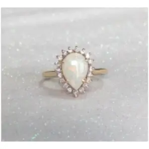 a ring featuring a pear shaped opal with diamond surround